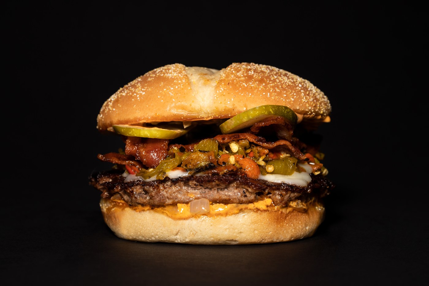 Hero burger — layered, lit, black background